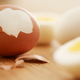 Partially peeled boiled egg next to fully peeled eggs
